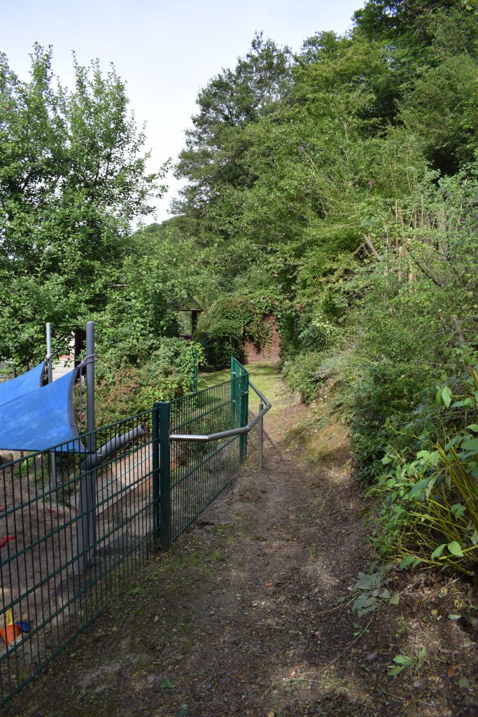 Auf dem Außengelände gibt es viele grüne Büsche und Bäume