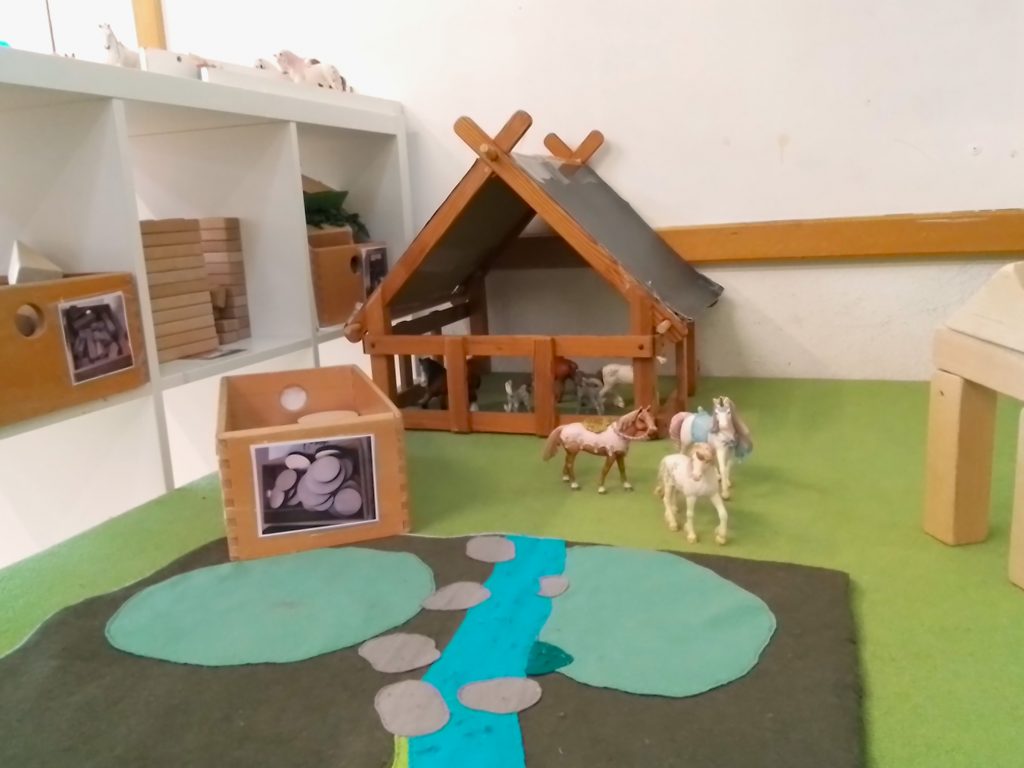 Der Pferdestall mit Spielpferden und Materialien aus denen Landschaften für die Pferde gebaut werden können.